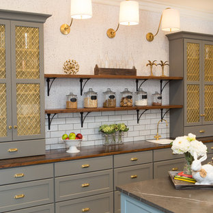 Inspiration for a large transitional u-shaped eat-in kitchen in Chicago with a farmhouse sink, shaker cabinets, grey cabinets, limestone benchtops, white splashback, subway tile splashback, black appliances, porcelain floors, with island and grey floor.