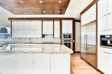 Moderne Küche mit flächenbündigen Schrankfronten, dunklen Holzschränken, Quarzit-Arbeitsplatte, Küchengeräten aus Edelstahl, hellem Holzboden und Kücheninsel in Calgary