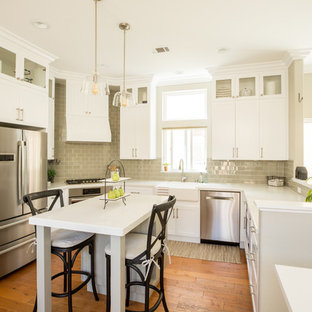 Ispirazione per una cucina ad U tradizionale con lavello stile country, ante in stile shaker, ante bianche, paraspruzzi grigio, elettrodomestici in acciaio inossidabile, parquet scuro, isola, pavimento marrone e top bianco