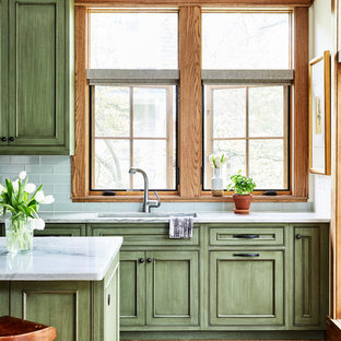 Immagine di una cucina american style di medie dimensioni con lavello sottopiano, ante con riquadro incassato, ante verdi, top in quarzo composito, paraspruzzi verde, paraspruzzi con piastrelle di vetro, elettrodomestici da incasso, pavimento in legno massello medio, isola, pavimento marrone e top grigio