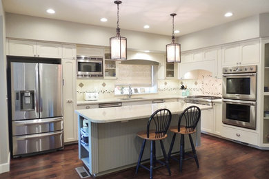 Inspiration for a mid-sized timeless l-shaped dark wood floor and brown floor open concept kitchen remodel in Sacramento with an undermount sink, quartz countertops, beige backsplash, stone tile backsplash, stainless steel appliances, an island, shaker cabinets and white cabinets