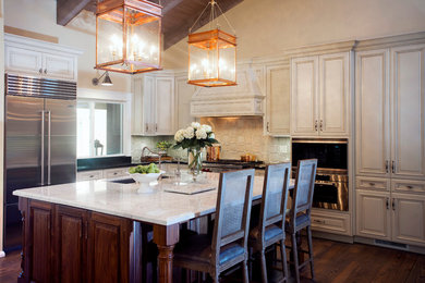 Inredning av ett modernt kök och matrum, med luckor med profilerade fronter, beige skåp, marmorbänkskiva, beige stänkskydd, mörkt trägolv och en köksö
