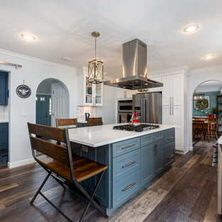 This is an example of a mid-sized transitional u-shaped kitchen pantry in Columbus with a farmhouse sink, shaker cabinets, white cabinets, quartzite benchtops, multi-coloured splashback, ceramic splashback, stainless steel appliances, vinyl floors, with island, multi-coloured floor and white benchtop.