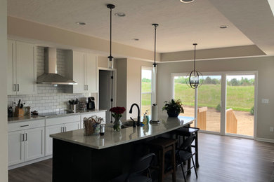 Example of a large transitional l-shaped medium tone wood floor and brown floor eat-in kitchen design in Columbus with an undermount sink, shaker cabinets, white cabinets, quartzite countertops, white backsplash, subway tile backsplash, stainless steel appliances, an island and gray countertops