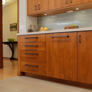 Design ideas for a mid-sized midcentury l-shaped eat-in kitchen in Los Angeles with a double-bowl sink, flat-panel cabinets, medium wood cabinets, quartz benchtops, grey splashback, glass tile splashback, panelled appliances, porcelain floors and a peninsula.