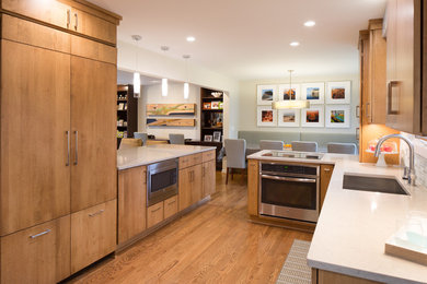 Example of a mid-sized trendy u-shaped medium tone wood floor and brown floor open concept kitchen design in Detroit with an undermount sink, flat-panel cabinets, medium tone wood cabinets, quartz countertops, multicolored backsplash, glass tile backsplash, stainless steel appliances and no island