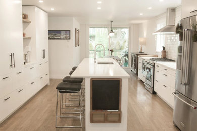 Inspiration for a large contemporary galley light wood floor and beige floor eat-in kitchen remodel in Vancouver with an undermount sink, flat-panel cabinets, white cabinets, quartz countertops, white backsplash, subway tile backsplash, stainless steel appliances, an island and white countertops