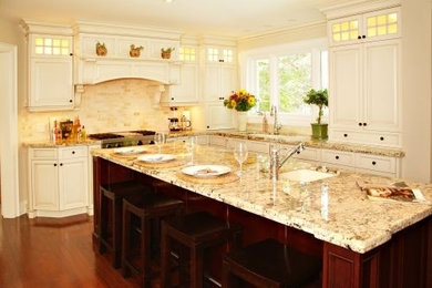 Mid-sized elegant l-shaped medium tone wood floor and brown floor eat-in kitchen photo in Other with an undermount sink, recessed-panel cabinets, travertine backsplash, an island, white cabinets, beige backsplash and stainless steel appliances