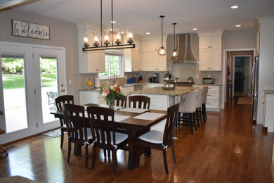 Eat-in kitchen - large transitional l-shaped medium tone wood floor eat-in kitchen idea in Cincinnati with an undermount sink, recessed-panel cabinets, white cabinets, granite countertops, subway tile backsplash, stainless steel appliances and an island