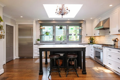 Inspiration for a large transitional medium tone wood floor and gray floor kitchen remodel in Other with a single-bowl sink, recessed-panel cabinets, white cabinets, granite countertops, white backsplash, subway tile backsplash, stainless steel appliances, an island and black countertops