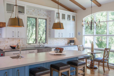 Mid-sized farmhouse l-shaped light wood floor and beige floor open concept kitchen photo in San Diego with a farmhouse sink, shaker cabinets, blue cabinets, quartz countertops, white backsplash, subway tile backsplash, stainless steel appliances, an island and gray countertops