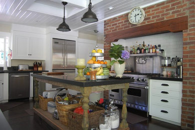オレンジカウンティにあるトラディショナルスタイルのおしゃれなキッチン (御影石カウンター、白いキャビネット、白いキッチンパネル、サブウェイタイルのキッチンパネル、シルバーの調理設備) の写真