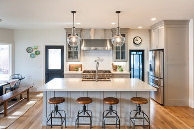 Transitional u-shaped light wood floor and brown floor eat-in kitchen photo in Salt Lake City with an undermount sink, shaker cabinets, gray cabinets, quartz countertops, white backsplash, stainless steel appliances and an island