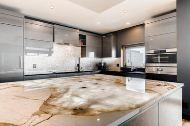 Large trendy l-shaped eat-in kitchen photo in Denver with an undermount sink, flat-panel cabinets, gray cabinets, granite countertops, mosaic tile backsplash, paneled appliances and an island