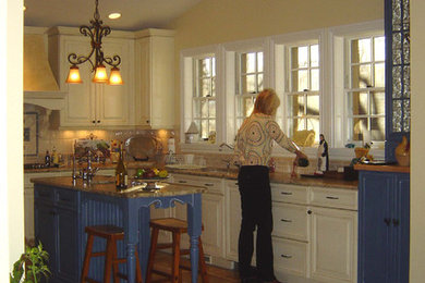 Idées déco pour une grande cuisine américaine classique en U avec un évier encastré, un placard avec porte à panneau surélevé, des portes de placard blanches, un plan de travail en granite, une crédence jaune, une crédence en céramique, un électroménager en acier inoxydable, un sol en carrelage de porcelaine et îlot.