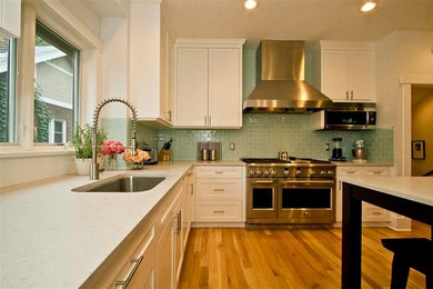 Exempel på ett mellanstort, avskilt klassiskt u-kök, med skåp i shakerstil, vita skåp, bänkskiva i kvarts, blått stänkskydd, stänkskydd i glaskakel, rostfria vitvaror och en köksö