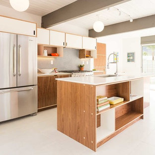 Mid-sized mid-century modern open concept kitchen photos - Example of a mid-sized 1950s galley white floor and porcelain tile open concept kitchen design in Los Angeles with an undermount sink, flat-panel cabinets, white cabinets, stainless steel appliances, an island, quartz countertops, gray backsplash and mosaic tile backsplash