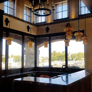 This is an example of an expansive mediterranean l-shaped eat-in kitchen in Las Vegas with a farmhouse sink, louvered cabinets, dark wood cabinets, onyx benchtops, stainless steel appliances, terrazzo floors, multiple islands and beige floor.