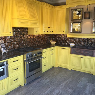 Photo of a large country l-shaped eat-in kitchen in Portland with a farmhouse sink, beaded inset cabinets, yellow cabinets, granite benchtops, brown splashback, ceramic splashback, stainless steel appliances, porcelain floors and no island.