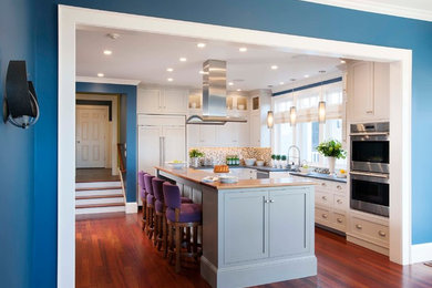 Inspiration for a large modern u-shaped dark wood floor kitchen pantry remodel in Burlington with a farmhouse sink, flat-panel cabinets, white cabinets, wood countertops, multicolored backsplash, paneled appliances and an island