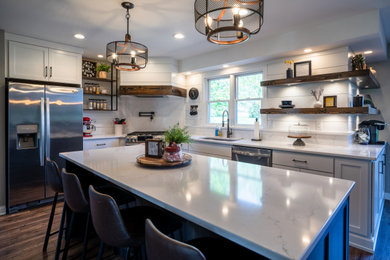 Example of a mid-sized farmhouse l-shaped vinyl floor and brown floor eat-in kitchen design in Other with a single-bowl sink, shaker cabinets, white cabinets, quartz countertops, white backsplash, quartz backsplash, stainless steel appliances, an island and white countertops