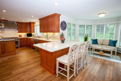 Example of a large classic u-shaped medium tone wood floor eat-in kitchen design in Orange County with a double-bowl sink, raised-panel cabinets, medium tone wood cabinets, quartzite countertops, beige backsplash, ceramic backsplash and stainless steel appliances