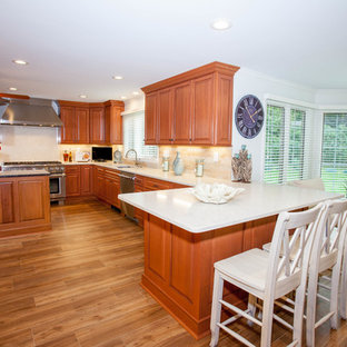 Inspiration for a large traditional u-shaped eat-in kitchen in Orange County with raised-panel cabinets, medium wood cabinets, quartzite benchtops, beige splashback, ceramic splashback, stainless steel appliances, a double-bowl sink and medium hardwood floors.