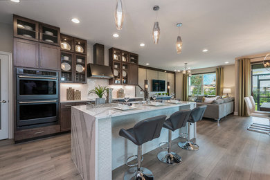 Example of a mid-sized trendy single-wall light wood floor and beige floor kitchen pantry design in Other with recessed-panel cabinets, dark wood cabinets, black appliances and an island