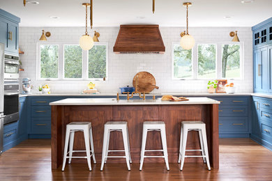 Eat-in kitchen - mid-sized transitional u-shaped dark wood floor and brown floor eat-in kitchen idea in Nashville with a farmhouse sink, shaker cabinets, blue cabinets, quartzite countertops, white backsplash, ceramic backsplash, stainless steel appliances, an island and white countertops