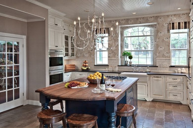Example of a large classic u-shaped travertine floor eat-in kitchen design in Austin with a farmhouse sink, white cabinets, white backsplash, subway tile backsplash, recessed-panel cabinets, solid surface countertops, stainless steel appliances and an island