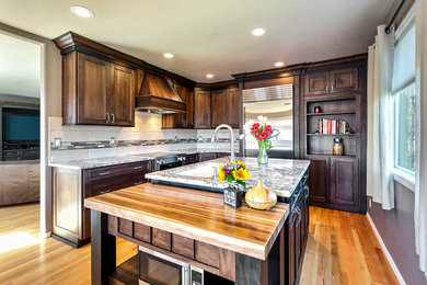 Mid-sized trendy l-shaped medium tone wood floor and brown floor open concept kitchen photo in Portland with shaker cabinets, dark wood cabinets, an island, a double-bowl sink, granite countertops, white backsplash, stone tile backsplash and stainless steel appliances