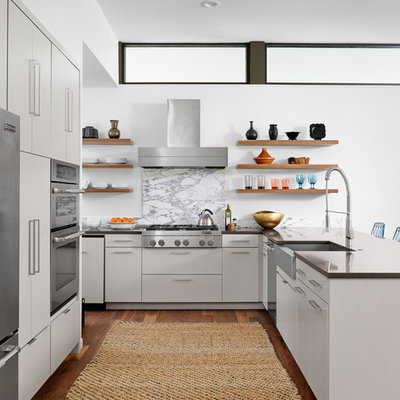Example of a 1960s u-shaped medium tone wood floor eat-in kitchen design in Austin with a farmhouse sink, flat-panel cabinets, gray cabinets, quartzite countertops, stone slab backsplash, stainless steel appliances and a peninsula