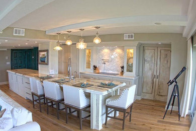 Large trendy single-wall light wood floor eat-in kitchen photo in Orlando with a farmhouse sink, shaker cabinets, white cabinets, marble countertops, white backsplash, porcelain backsplash, stainless steel appliances and an island