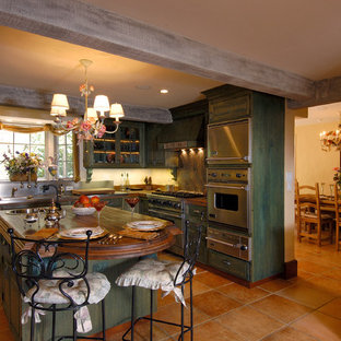 Inspiration for a mid-sized tropical l-shaped open plan kitchen in Hawaii with an integrated sink, raised-panel cabinets, green cabinets, wood benchtops, green splashback, stone slab splashback, stainless steel appliances, with island and brown benchtop.