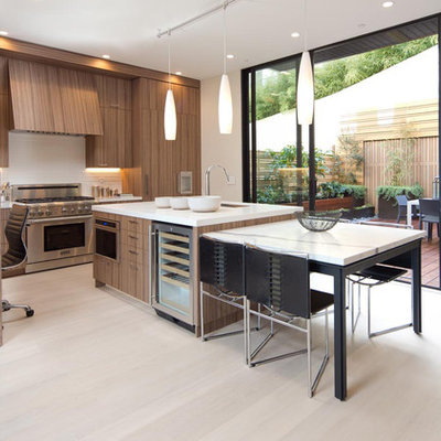 Mid-sized trendy l-shaped light wood floor eat-in kitchen photo in San Francisco with an undermount sink, flat-panel cabinets, medium tone wood cabinets, white backsplash, paneled appliances and an island