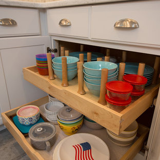 Design ideas for a mid-sized beach style u-shaped kitchen in Boston with a farmhouse sink, recessed-panel cabinets, white cabinets, quartz benchtops, grey splashback, stone tile splashback, stainless steel appliances, ceramic floors, a peninsula and grey floor.