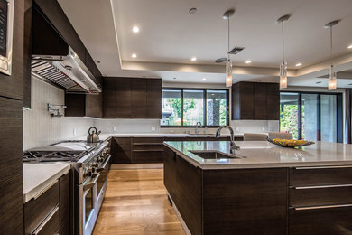 Photo of a large classic l-shaped open plan kitchen in Los Angeles with brown cabinets, stainless steel appliances, an island and brown floors.