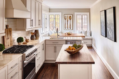 Foto på ett mellanstort funkis kök, med skåp i shakerstil, vita skåp, en köksö, en undermonterad diskho, vitt stänkskydd, stänkskydd i tunnelbanekakel, rostfria vitvaror, mörkt trägolv och brunt golv