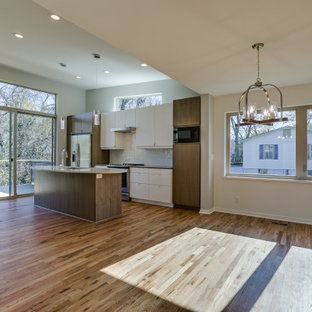 Mid-sized mid-century modern open concept kitchen pictures - Example of a mid-sized 1960s single-wall medium tone wood floor and brown floor open concept kitchen design in Kansas City with an undermount sink, flat-panel cabinets, medium tone wood cabinets, quartzite countertops, white backsplash, ceramic backsplash, stainless steel appliances, an island and white countertops
