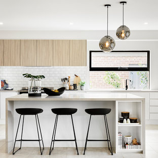 This is an example of a modern l-shaped kitchen in Melbourne with an undermount sink, flat-panel cabinets, light wood cabinets, white splashback, subway tile splashback, stainless steel appliances, with island, beige floor and beige benchtop.