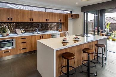 Moderne Küche mit flächenbündigen Schrankfronten, hellbraunen Holzschränken, Küchenrückwand in Braun, Küchengeräten aus Edelstahl und Kücheninsel in Brisbane