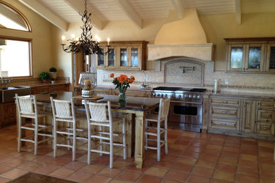 Mountain style terra-cotta tile kitchen photo in Santa Barbara with raised-panel cabinets, distressed cabinets, granite countertops, mosaic tile backsplash, stainless steel appliances, an island and a farmhouse sink