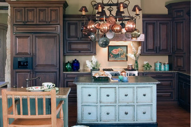 Immagine di una grande cucina stile rurale con ante con bugna sagomata, ante in legno bruno, top in granito, elettrodomestici da incasso e pavimento in legno massello medio