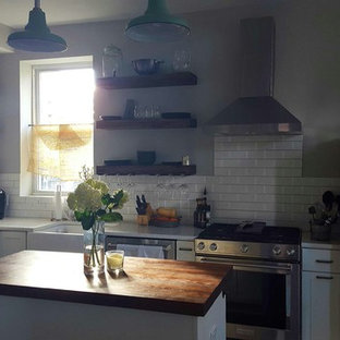 This is an example of a small shabby-chic style l-shaped eat-in kitchen in DC Metro with shaker cabinets, white cabinets, wood benchtops, white splashback, porcelain splashback and with island.