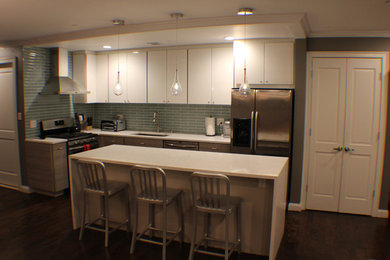 Mid-sized trendy l-shaped kitchen photo in New York with flat-panel cabinets, white cabinets, blue backsplash, subway tile backsplash, stainless steel appliances and an island