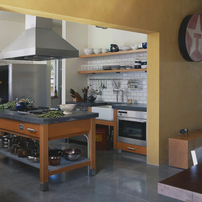 Urban eat-in kitchen photo in Seattle with stainless steel appliances, a farmhouse sink, open cabinets, medium tone wood cabinets, concrete countertops, white backsplash and subway tile backsplash