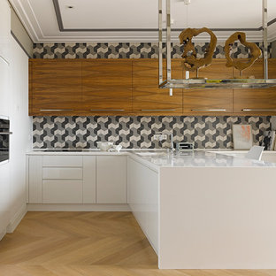 Design ideas for a contemporary u-shaped open plan kitchen in Moscow with flat-panel cabinets, multi-coloured splashback, white cabinets, light hardwood floors, a peninsula, an integrated sink, solid surface benchtops, ceramic splashback and black appliances.