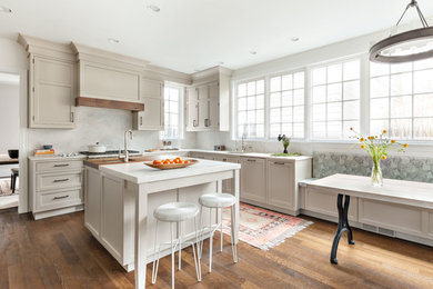 Example of a mid-sized classic l-shaped dark wood floor and brown floor eat-in kitchen design in New York with an undermount sink, white countertops, an island, shaker cabinets, beige cabinets, white backsplash, stone slab backsplash and paneled appliances