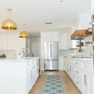 Ispirazione per una cucina ad U classica con ante in stile shaker, ante bianche, paraspruzzi bianco, elettrodomestici in acciaio inossidabile, parquet chiaro, pavimento beige e top bianco