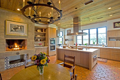 Eat-in kitchen - large mediterranean terra-cotta tile and orange floor eat-in kitchen idea in Atlanta with a double-bowl sink, flat-panel cabinets, light wood cabinets, stainless steel appliances and an island
